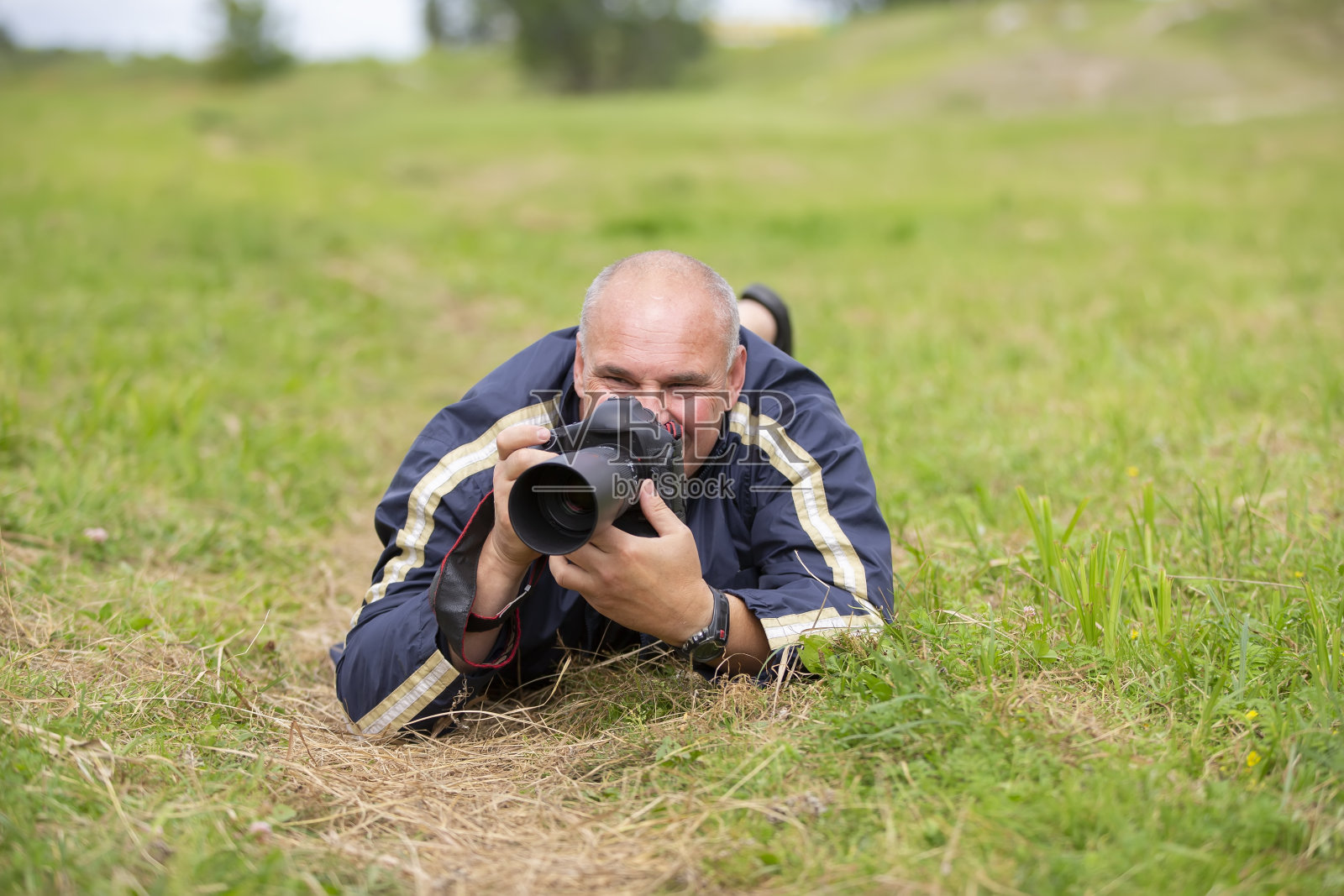 摄影师拿着照相机躺在草地上照片摄影图片