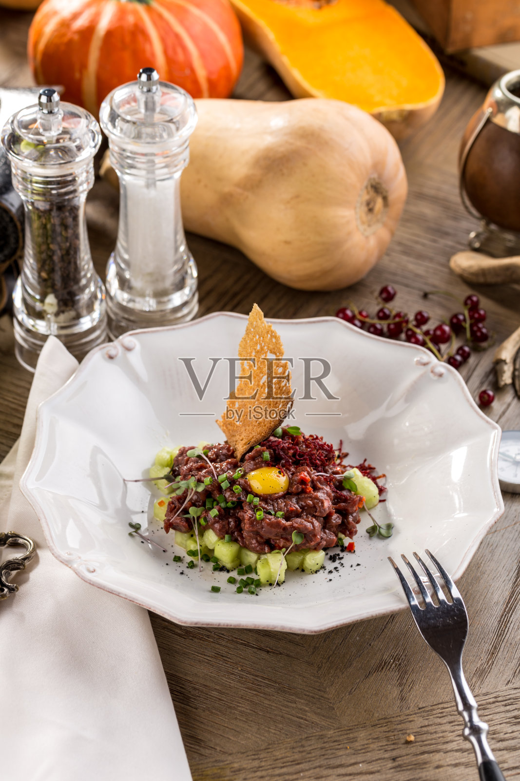 木桌上的鞑靼牛排、吐司面包和黄瓜照片摄影图片