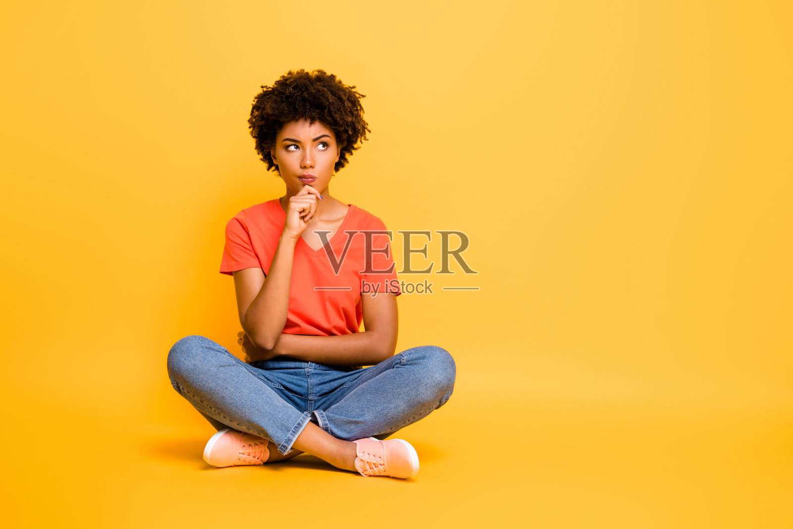 完整的身体尺寸照片沉思解决决定的女友坐在她的腿交叉穿着牛仔裤牛仔t恤触摸她的下巴孤立在黄色鲜艳的背景照片摄影图片