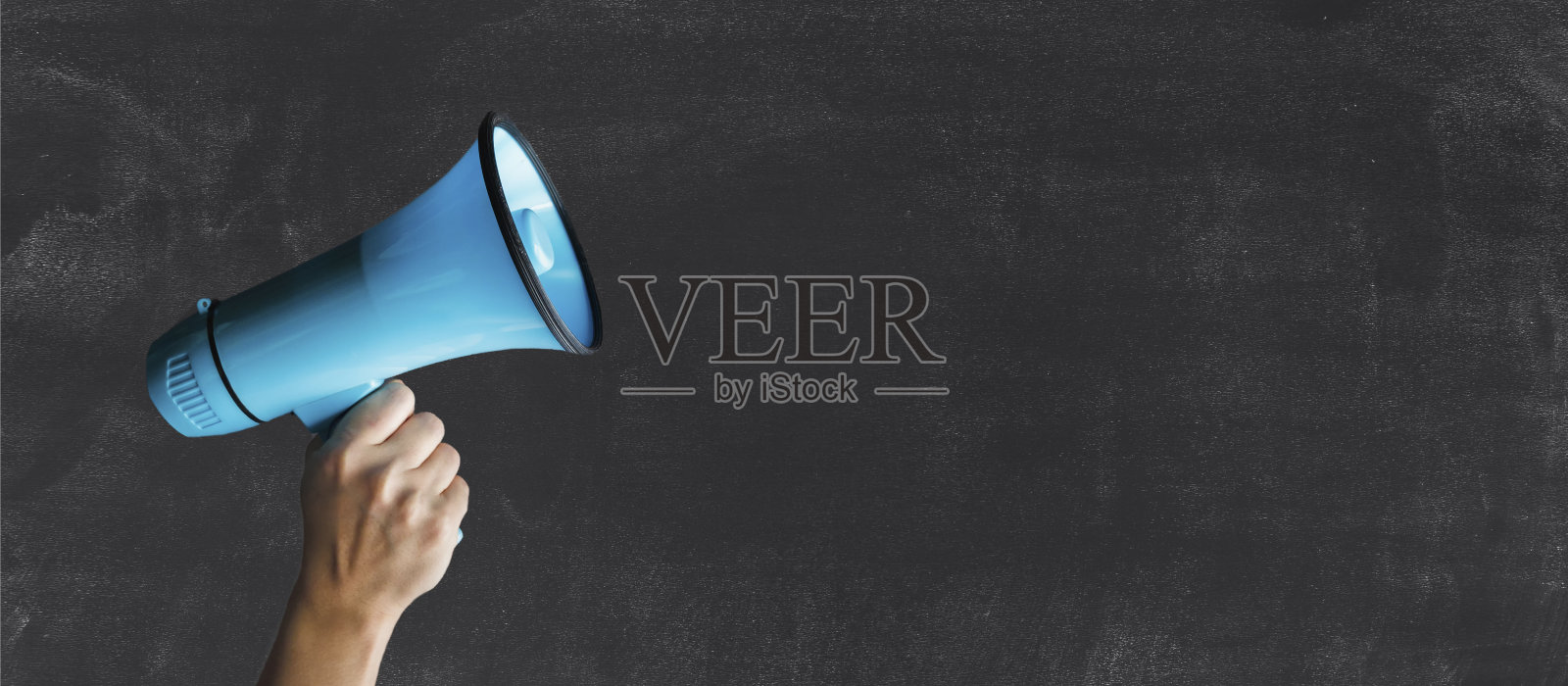 创造性的平坦。女人的手举起，举着扩音器。特写的人手拿着扩音器对着黑板照片摄影图片