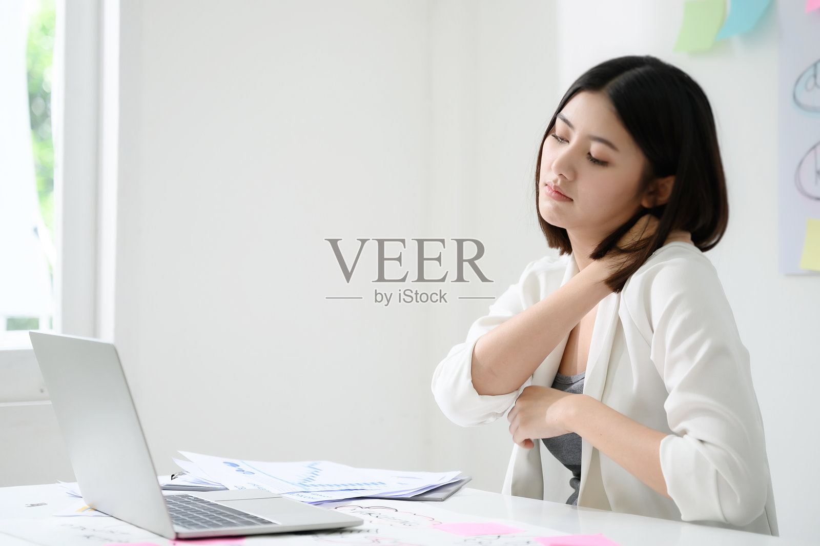 办公室综合症的概念。年轻的亚洲女商人在长时间使用电脑后感到脖子痛照片摄影图片