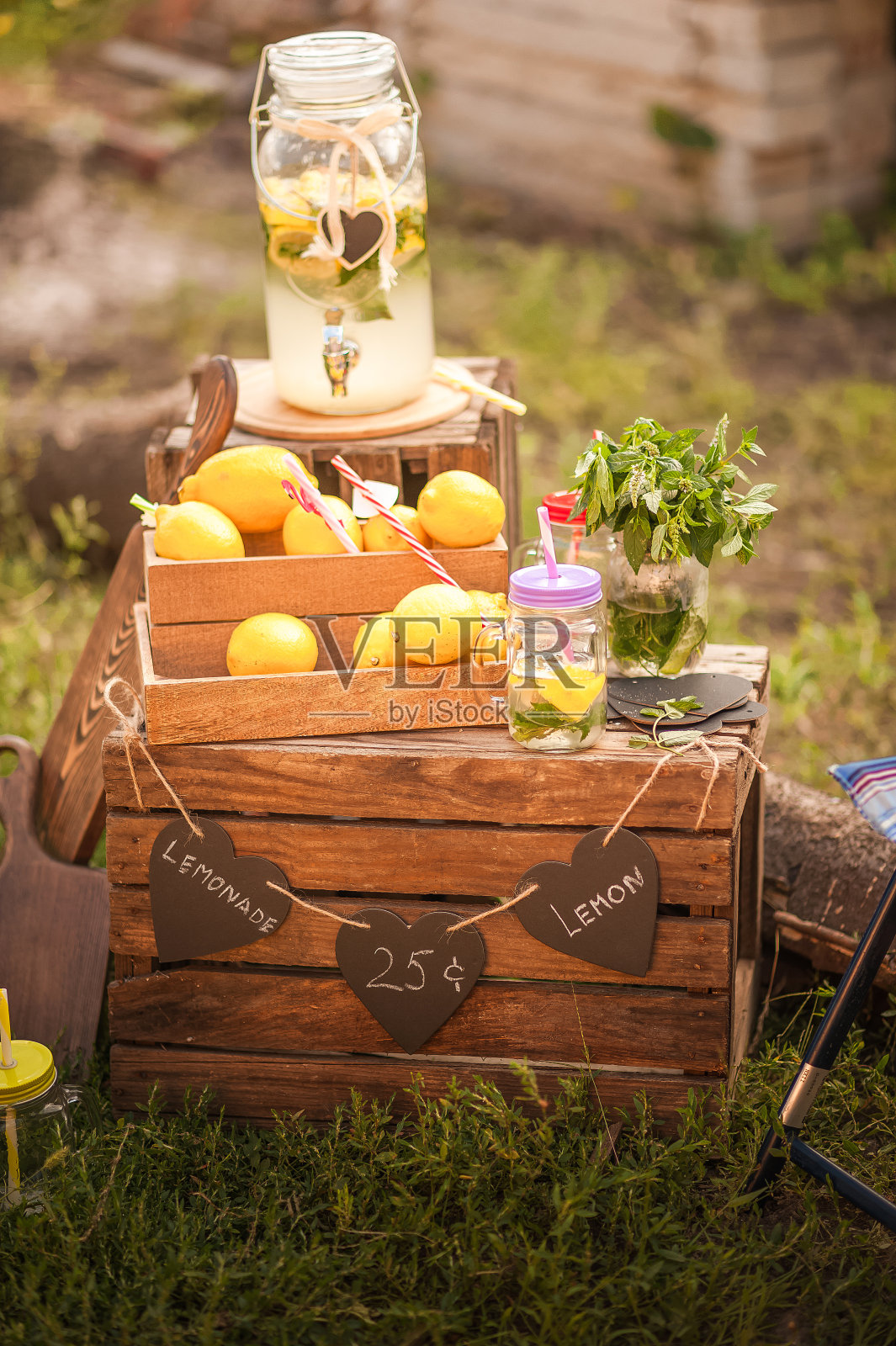 公园里的木制柠檬水摊。户外自制柠檬水摊位的标志和一个小型企业或金钱的概念。在公园的绿色草坪上有一个放着柠檬水的木制柜台。一个可爱的夏天le照片摄影图片