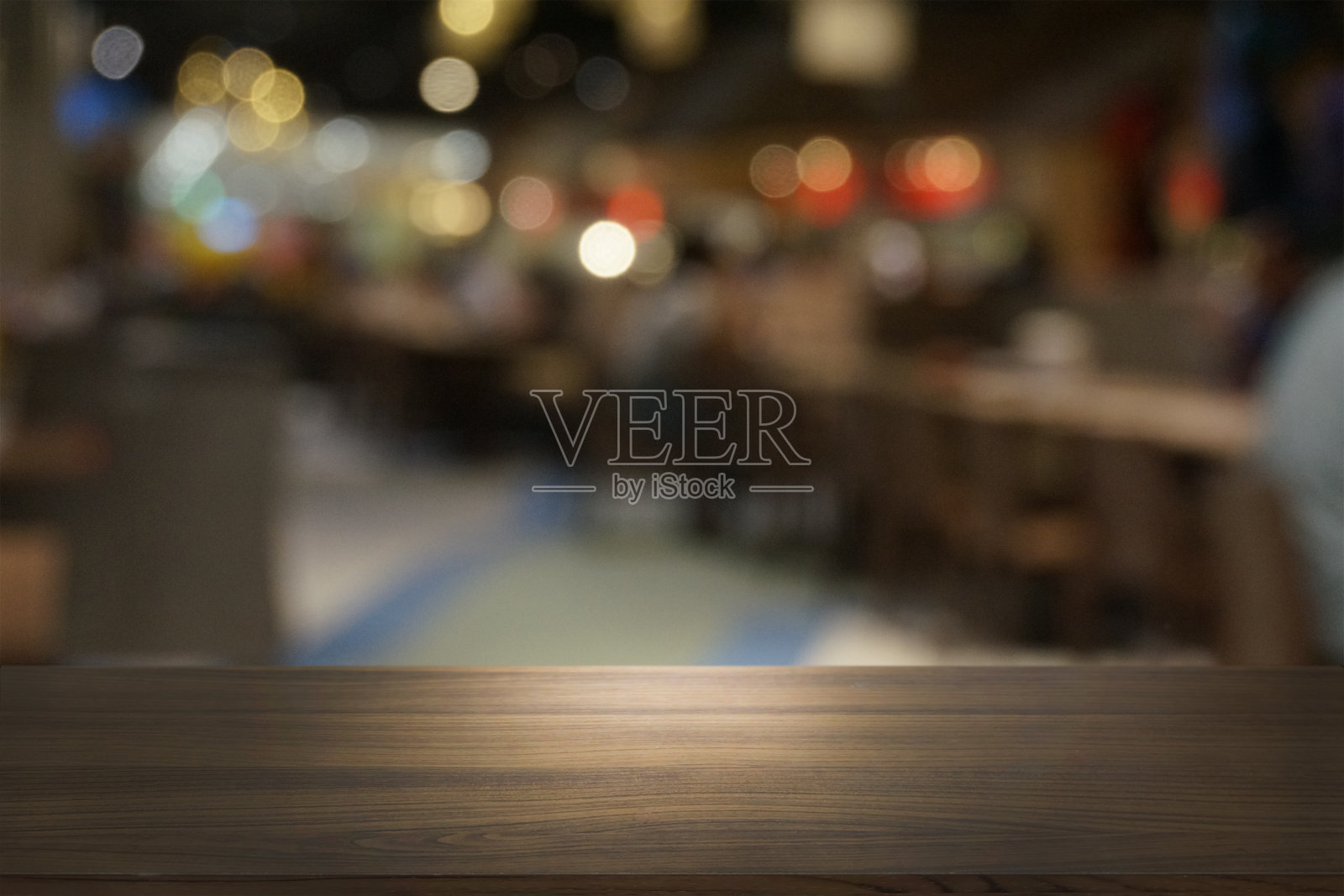 空荡荡的深色木桌前面抽象模糊的散景餐厅背景。可用于展示或蒙太奇您的产品。模拟空间。照片摄影图片