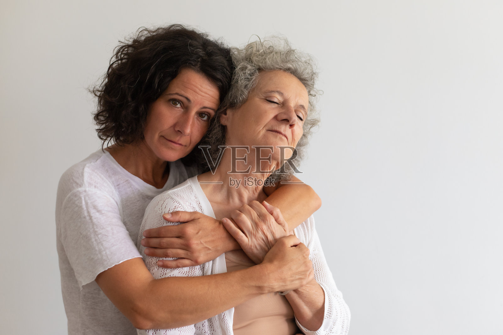 严肃的成年女儿在工作室里拥抱年长的母亲照片摄影图片