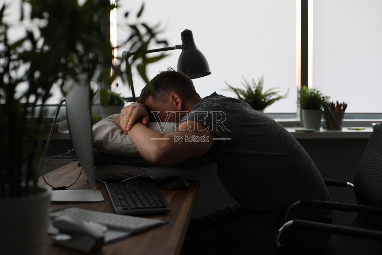 男人晚上睡在办公室的桌子上照片摄影图片