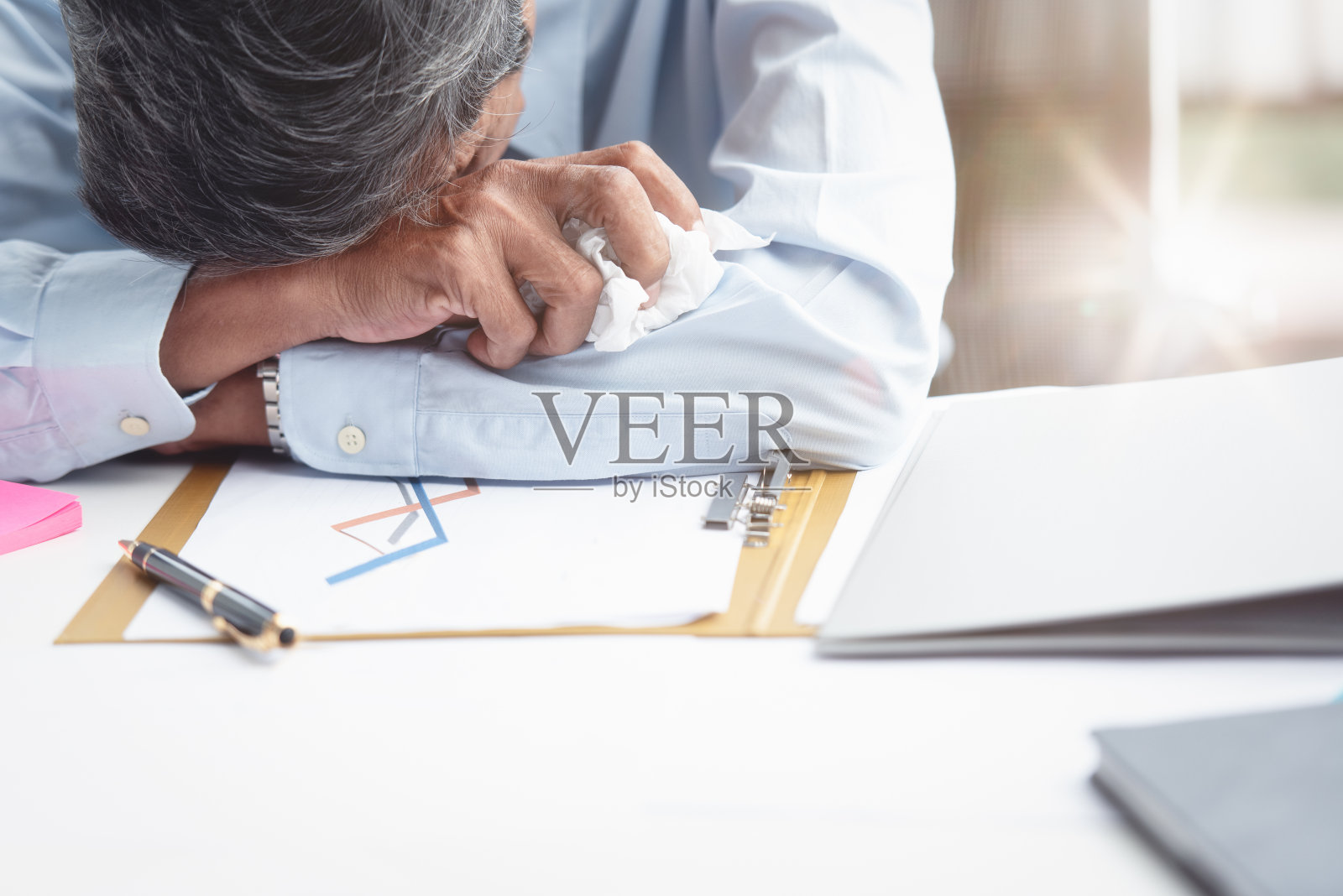 股票市场销售报告失败后，这位商人坐在办公室的办公桌前，手里拿着一张纸巾。他累了，又哭又沮丧。经营理念。过度劳累和睡眠。照片摄影图片