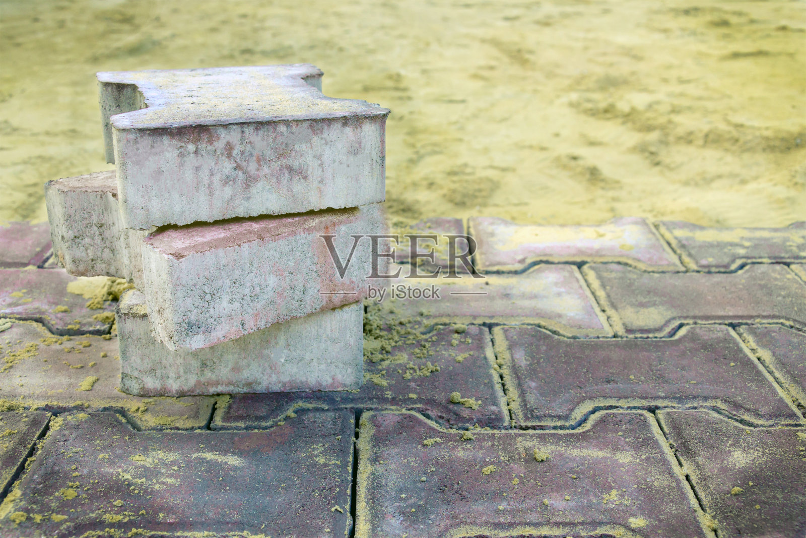 几块铺路板躺在人行道、道路、广场的修复处，背景是沙子。铺路板的铺设。铺装板制作广告照片摄影图片