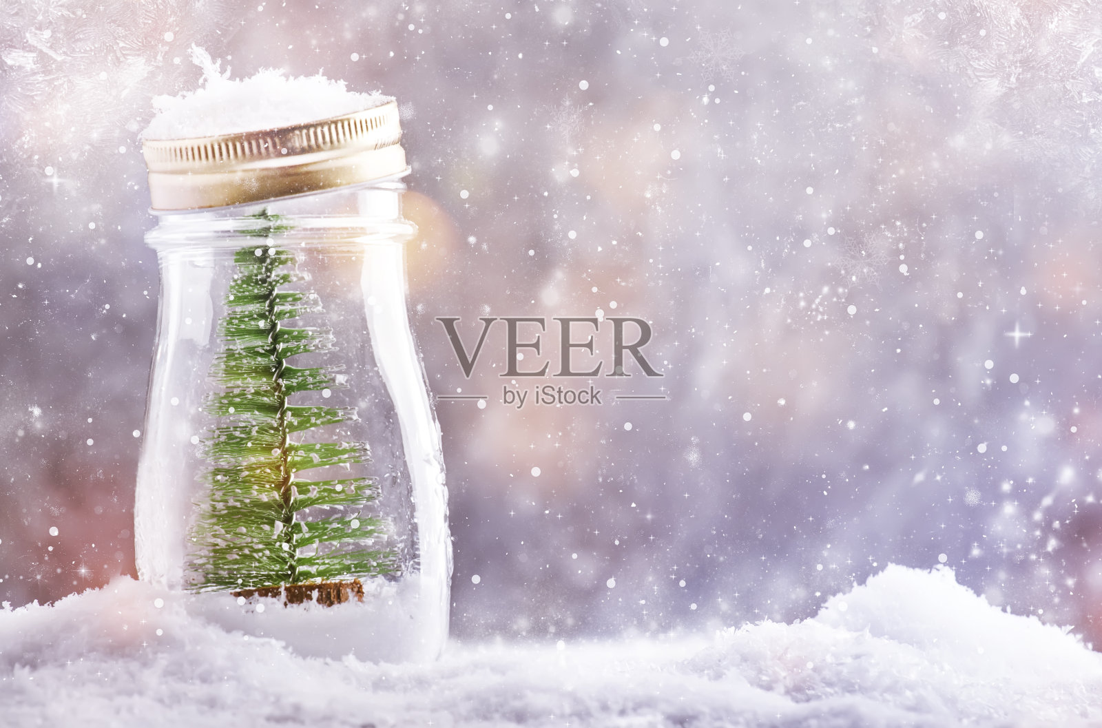 小圣诞树放在玻璃罐里，新年背景白雪皑皑，圣诞概念照片摄影图片