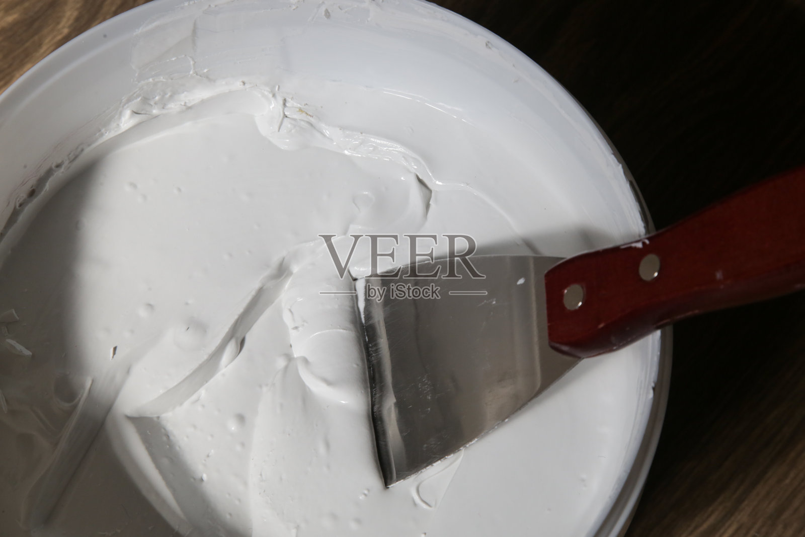 男子用油灰刀抹墙，特写图像。墙面固定及涂装准备。照片摄影图片