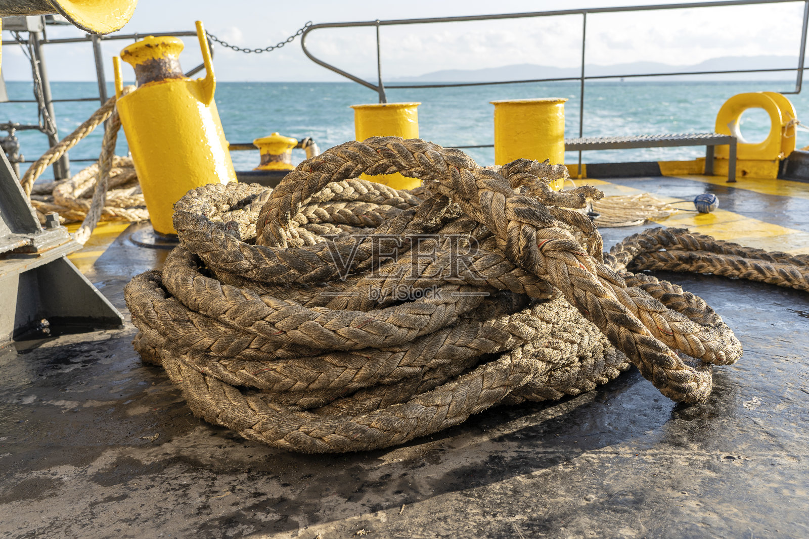 渡船的甲板上随着一根粗大的系泊绳和碧蓝的海水波浪起伏，泰国。近距离照片摄影图片