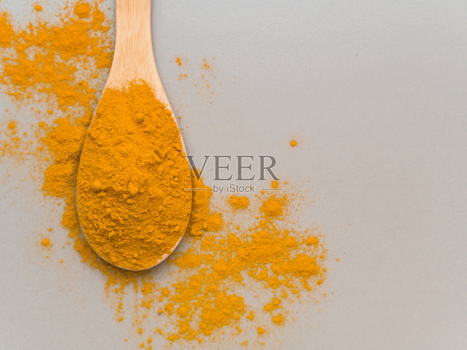 姜黄粉。传统印度黄金健康香料在木勺上灰色背景。俯视图照片摄影图片