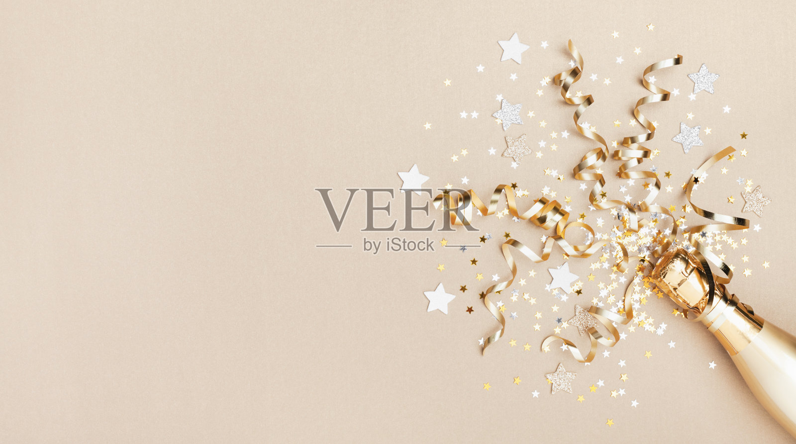 庆祝背景与金色的香槟瓶，五彩缤纷的星星和派对彩带。圣诞节、生日或婚礼概念。平的。照片摄影图片