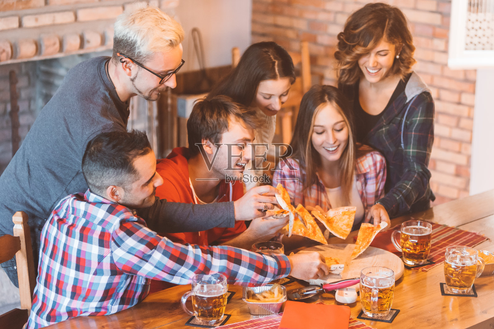 一群年轻人在一起玩，吃着披萨，喝着啤酒——青少年朋友们享受聚会和庆祝照片摄影图片