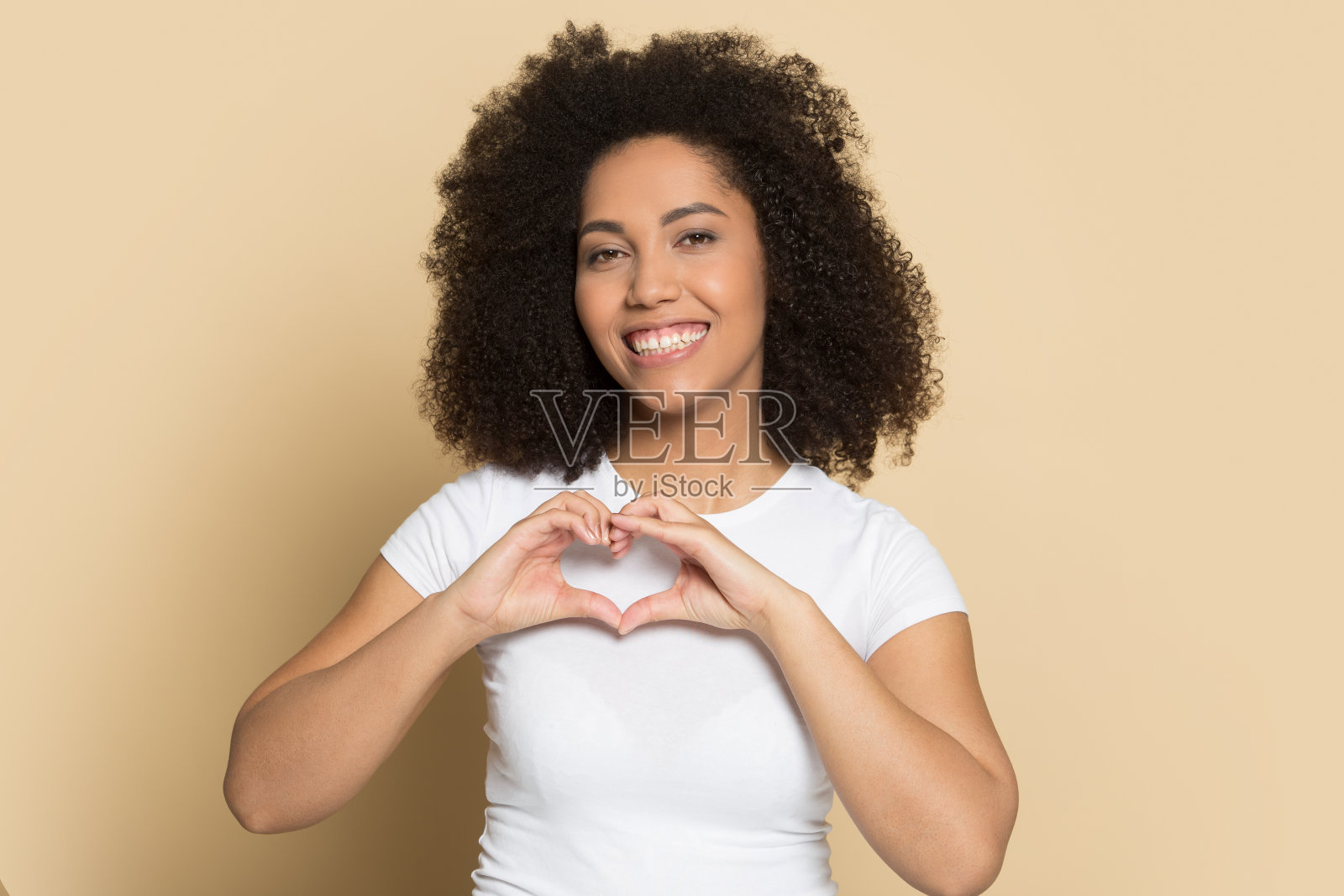 微笑的混血女孩看着相机做心的手势照片摄影图片