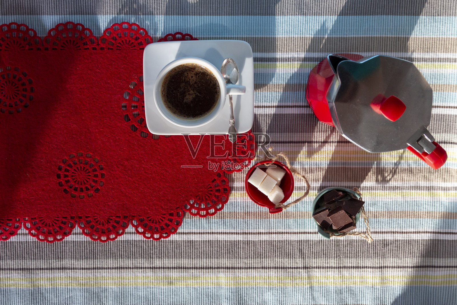 一杯热咖啡，意大利咖啡机，摩卡咖啡壶，糖碗和巧克力在蓝色的红色厨房桌子在阳光明媚的早晨，俯视图，平躺照片摄影图片