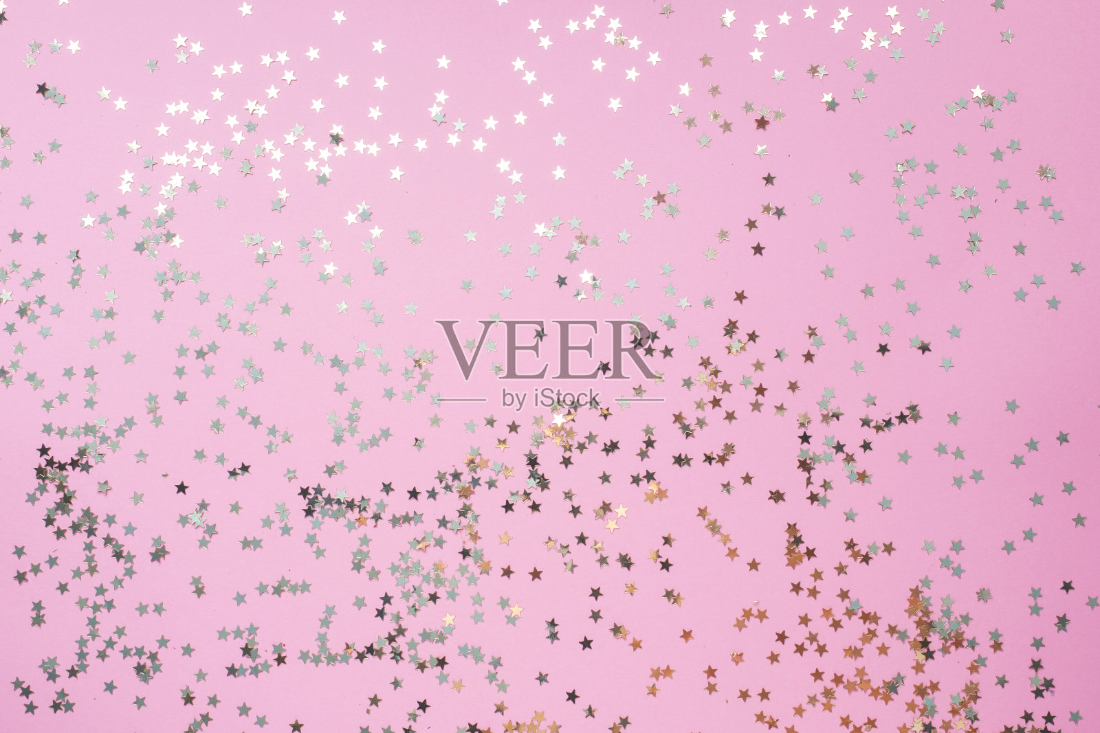 金色星星的五彩纸屑在粉红色的背景上闪闪发光。节日色彩柔和的背景。照片摄影图片