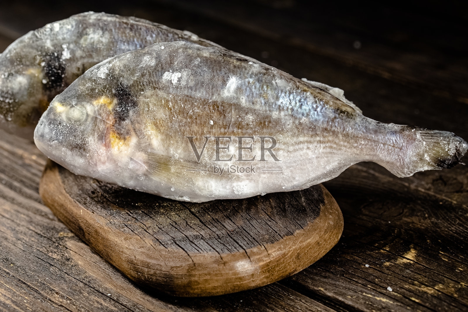 一块块红白鱼片装在包装里冷冻在塑料硬纸板上，打开后，放在深色木板上，暗灯下，俯视图，四周照片摄影图片