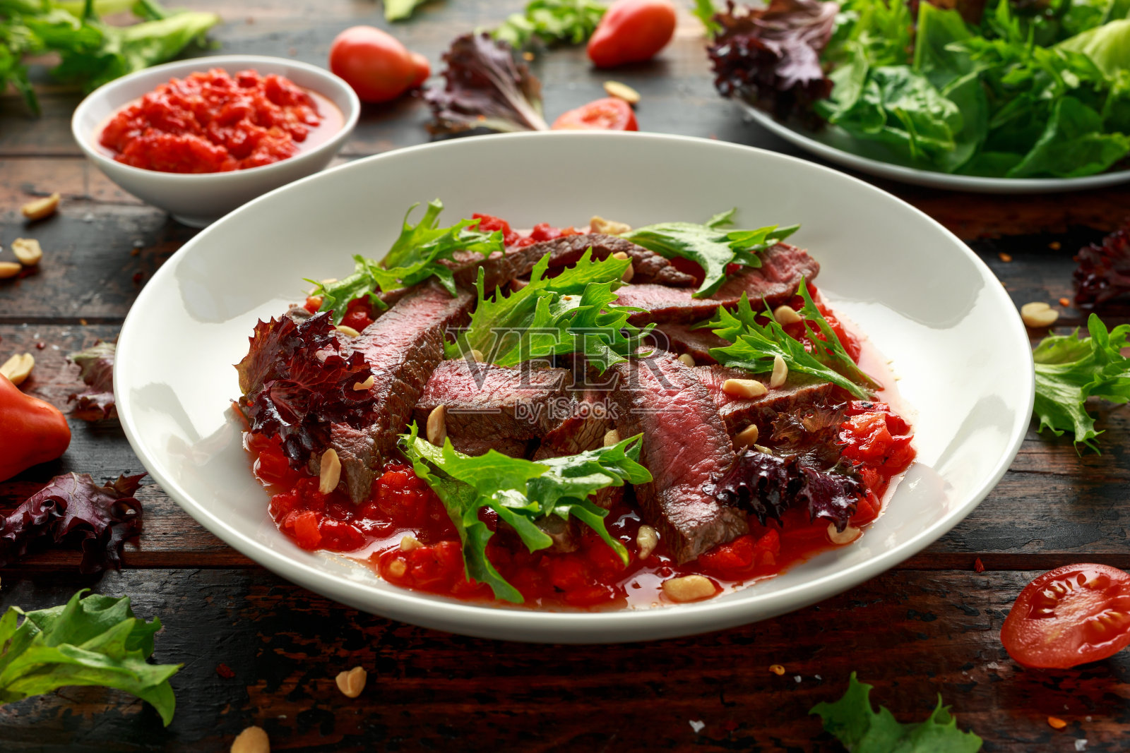 牛扒配罗美斯科沙司，坚果和蔬菜放在白盘子里照片摄影图片