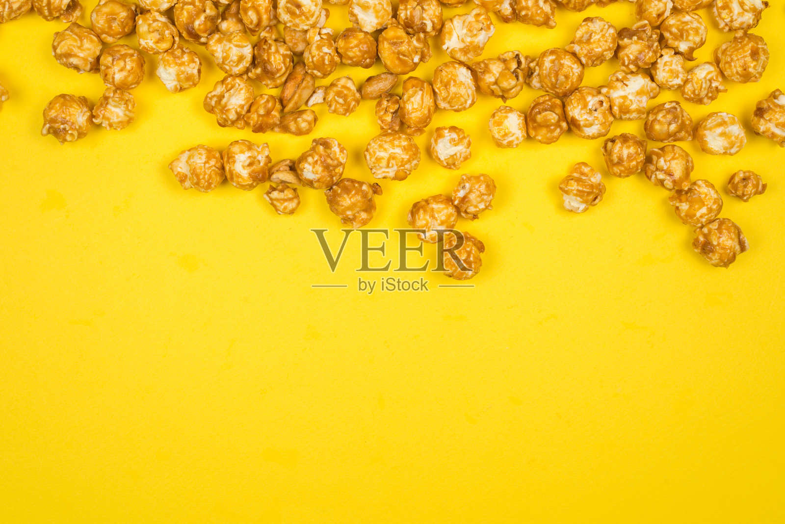 黄色背景上的焦糖爆米花。副本的空间。照片摄影图片