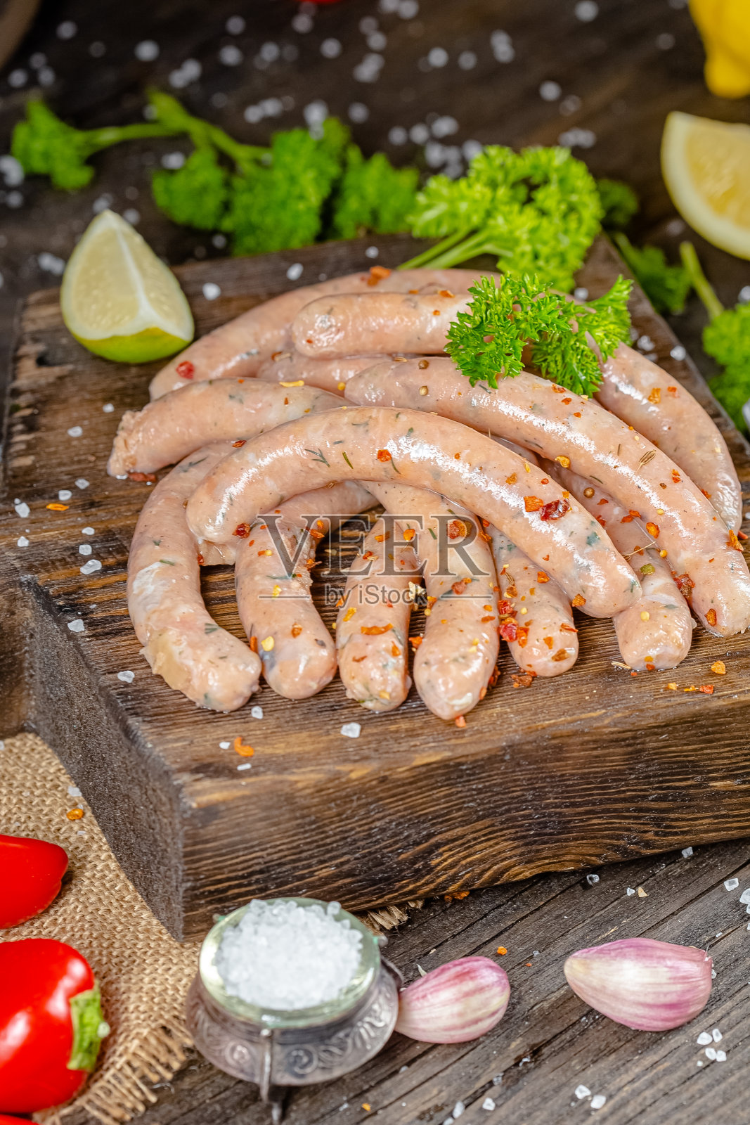 自制的热狗香肠，由红白鱼肉生而成，放在一个古老的乡村碗盘里，叉子，刀叉，香料，药草，从不同的角度，放在一个木头砧板上，光线昏暗照片摄影图片