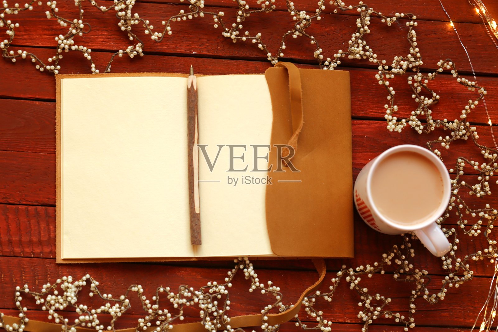 圣诞节的待办事项清单。红木桌上放着一个带笔的笔记本、一杯咖啡和复古的圣诞花环。冬天的假期。圣诞节的时候照片摄影图片
