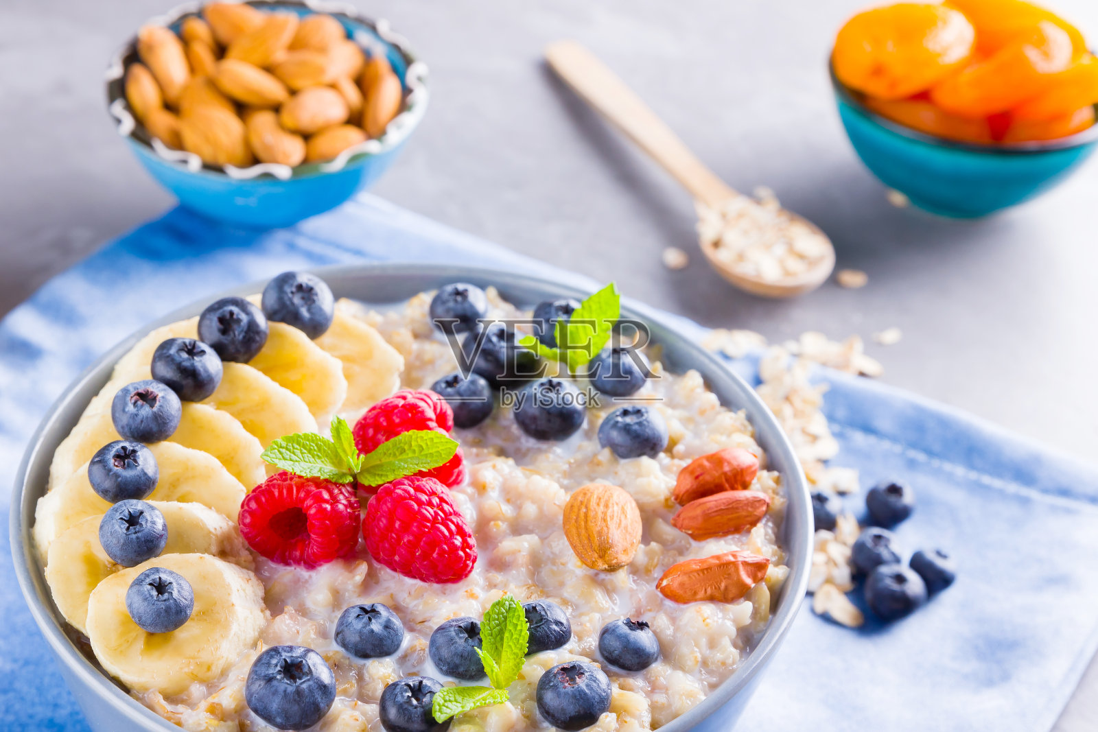 健康的自制燕麦，浆果和坚果早餐。燕麦片加水果，坚果和蜂蜜。燕麦片配蓝莓、香蕉和覆盆子照片摄影图片