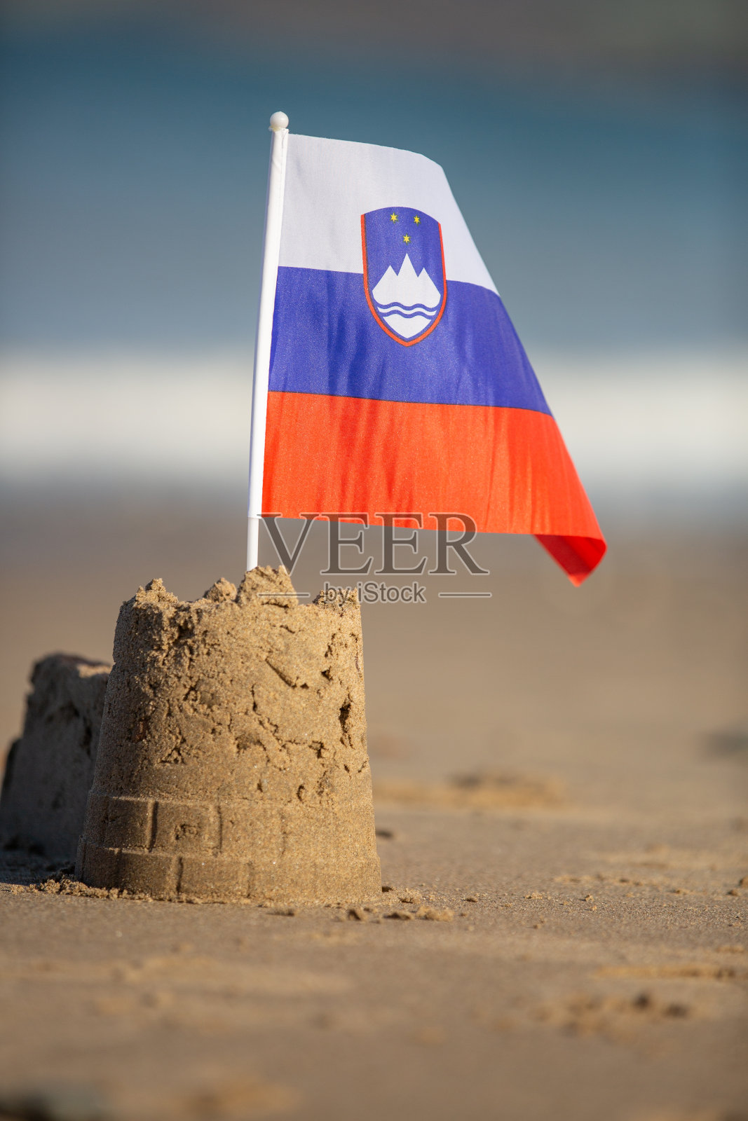 斯洛文尼亚国旗在一个城堡形状的沙堡在一个美丽的海滩在灿烂的阳光照片摄影图片