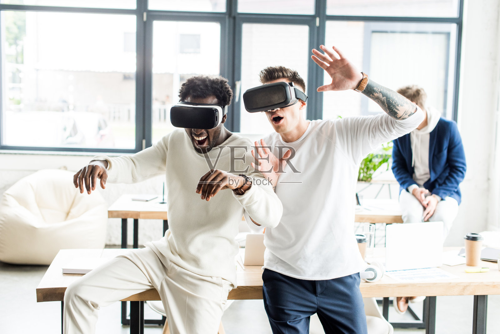 两位来自不同文化背景的同事在办公室用虚拟现实头盔打手势照片摄影图片