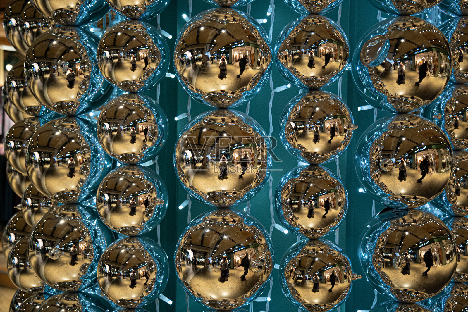 一排排闪亮的镜面玻璃球，蓝色的灯光和模糊的背景。扭曲的反射在金色光泽的表面圣诞球饰品。抽象的背景。创作的背景照片摄影图片