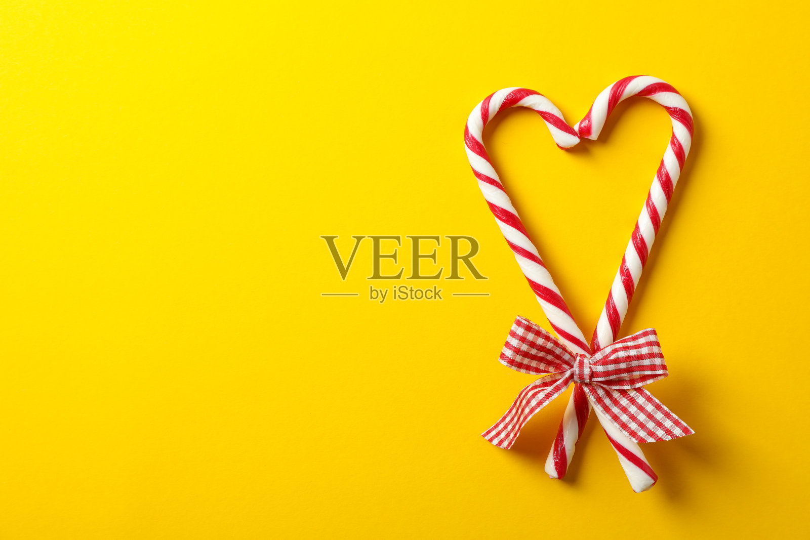 黄色背景上带蝴蝶结的糖果拐杖，文字空间照片摄影图片