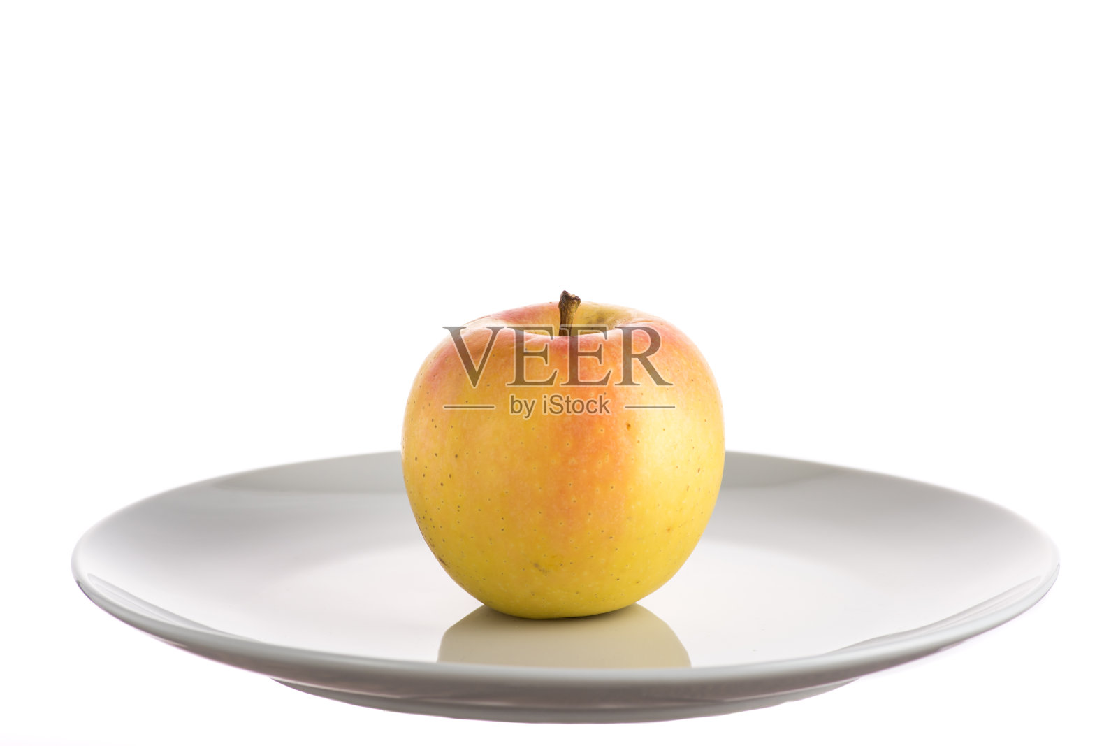 红色和黄色的苹果在白色的背景白色的盘子上照片摄影图片