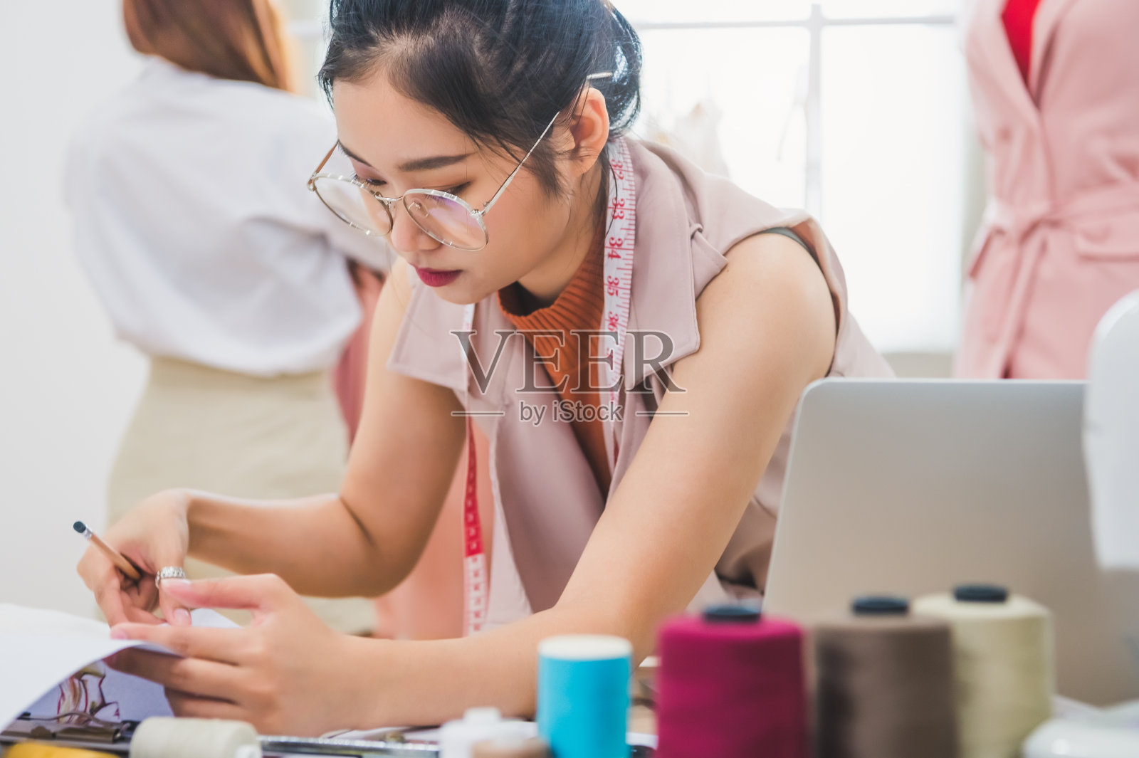 富有魅力的亚洲女时装设计师，在服装店工作，有客户背景。时尚的时尚女性创造新的布料设计系列。裁缝和缝纫。人们生活方式的概念照片摄影图片