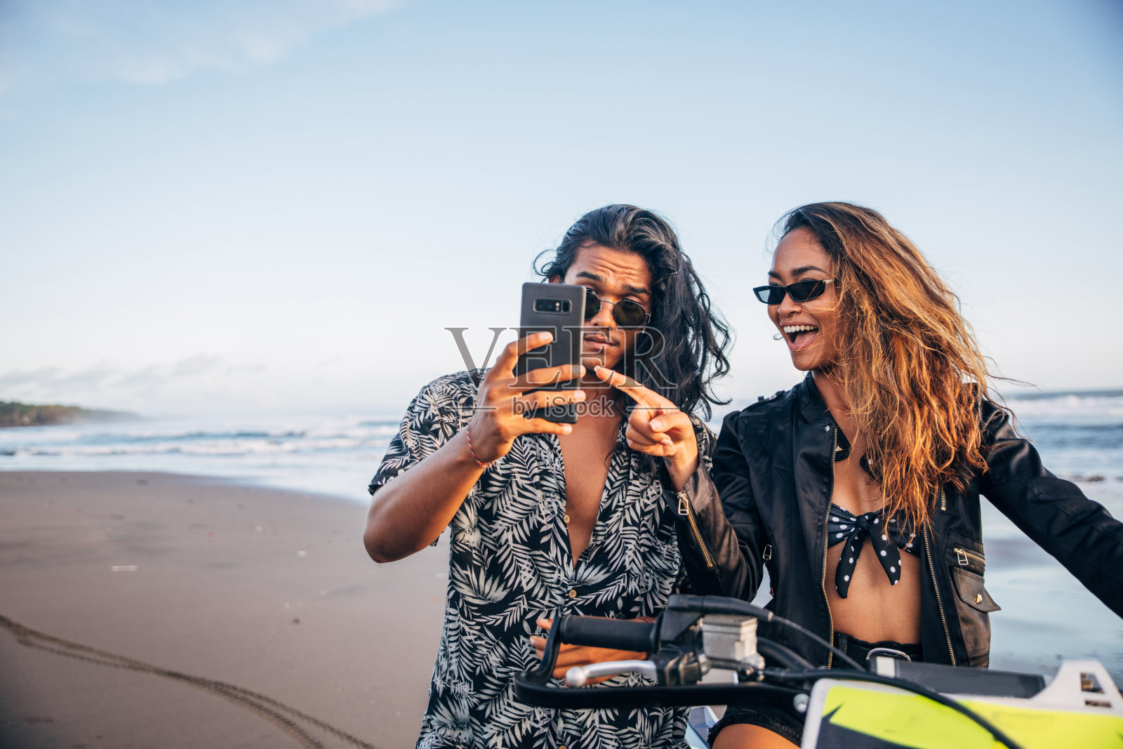 年轻夫妇在海滩上使用智能手机照片摄影图片