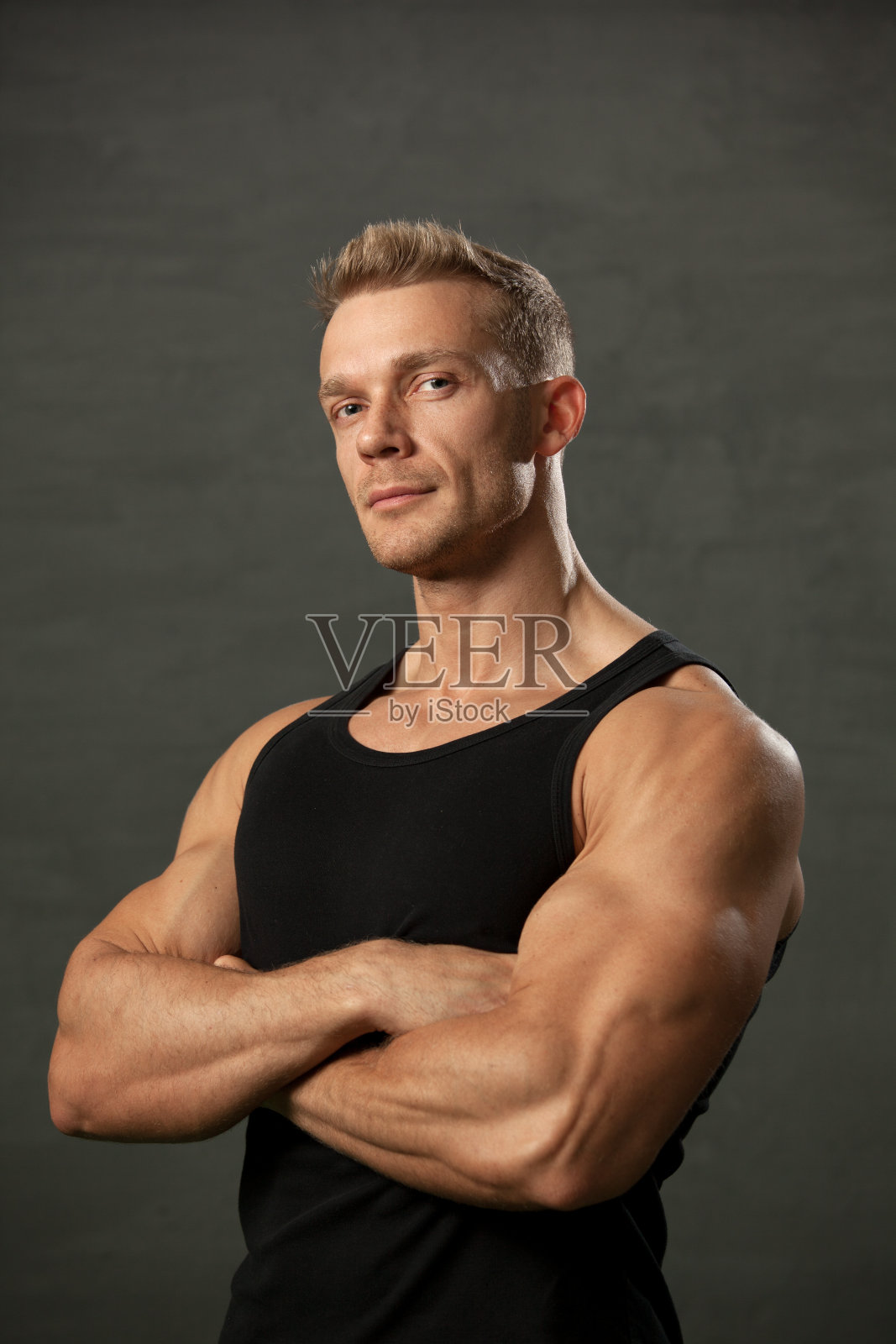 一名40岁的男运动员在灰色背景下穿着黑色背心照片摄影图片