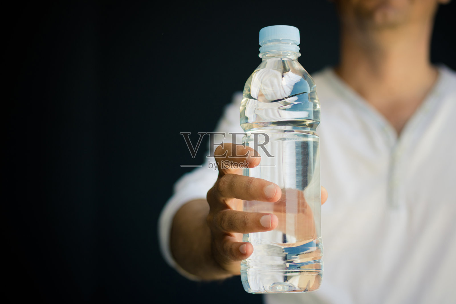 一个不认识的人拿着一瓶水。照片摄影图片