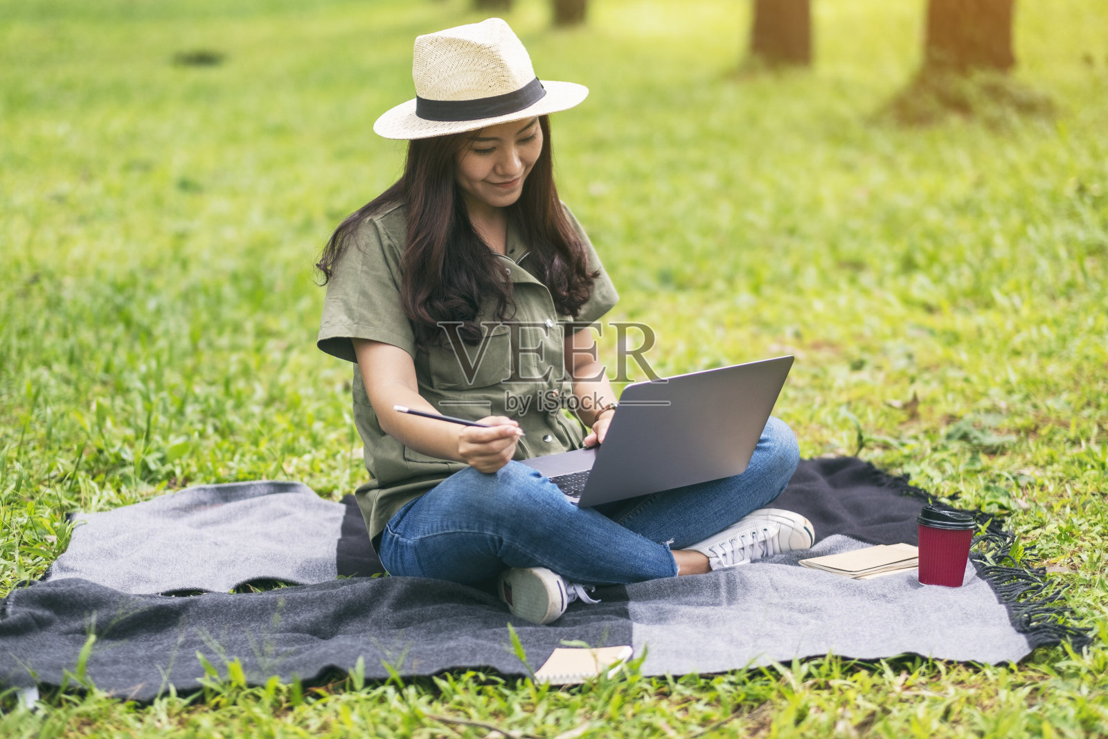 坐在公园里一边工作一边用笔记本电脑打字的女人照片摄影图片