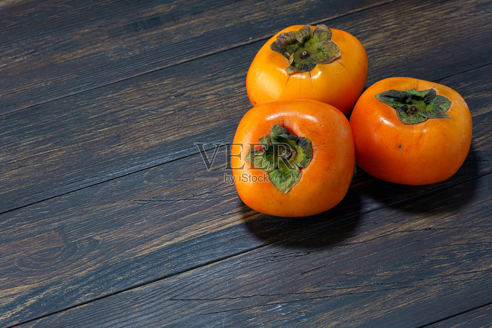 新鲜成熟的柿子放在木桌上照片摄影图片