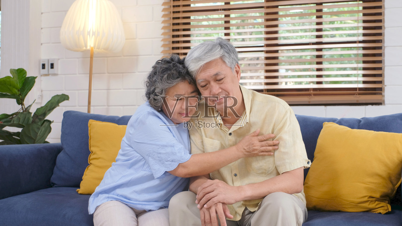年长的亚洲夫妇在客厅沙发上互相安慰，退休生活照片摄影图片