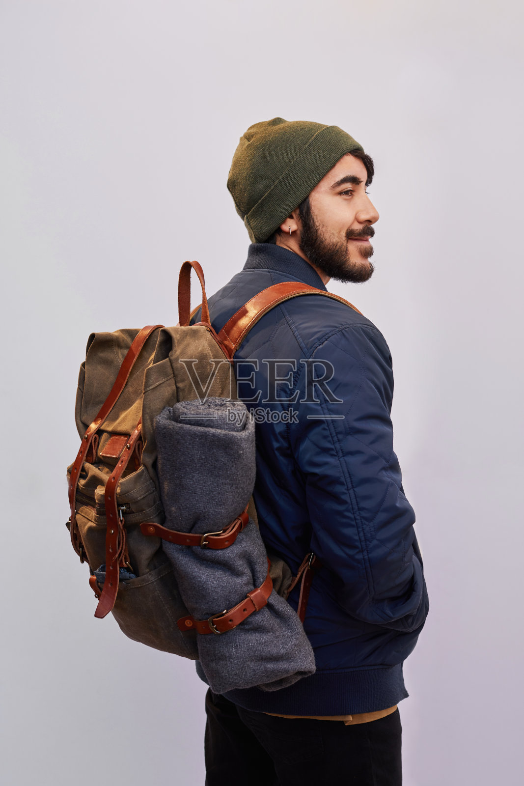 在灰色的背景下，穿着登山装备的年轻男子微笑着照片摄影图片