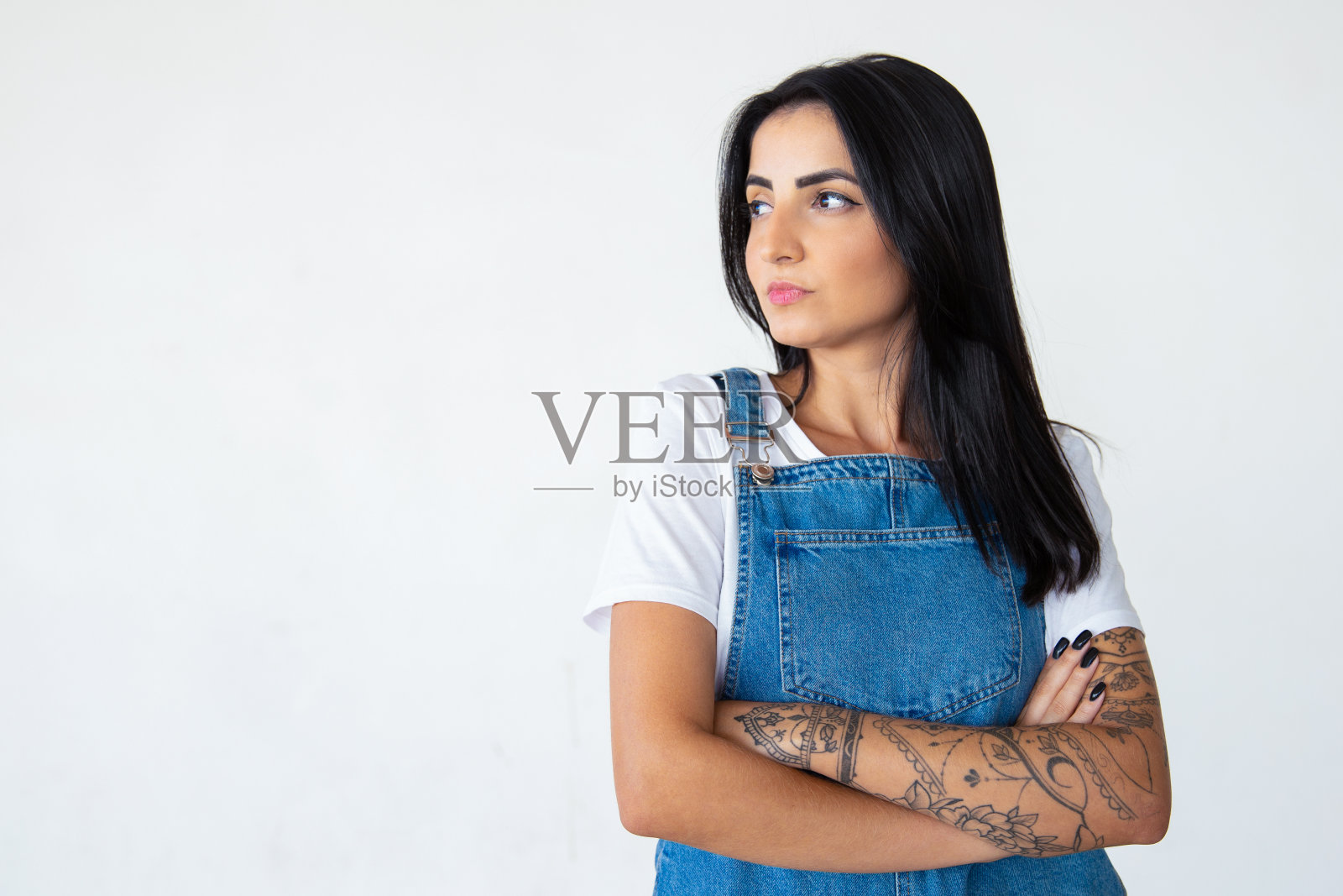 严肃的年轻褐发女子，双臂交叉看着一边照片摄影图片