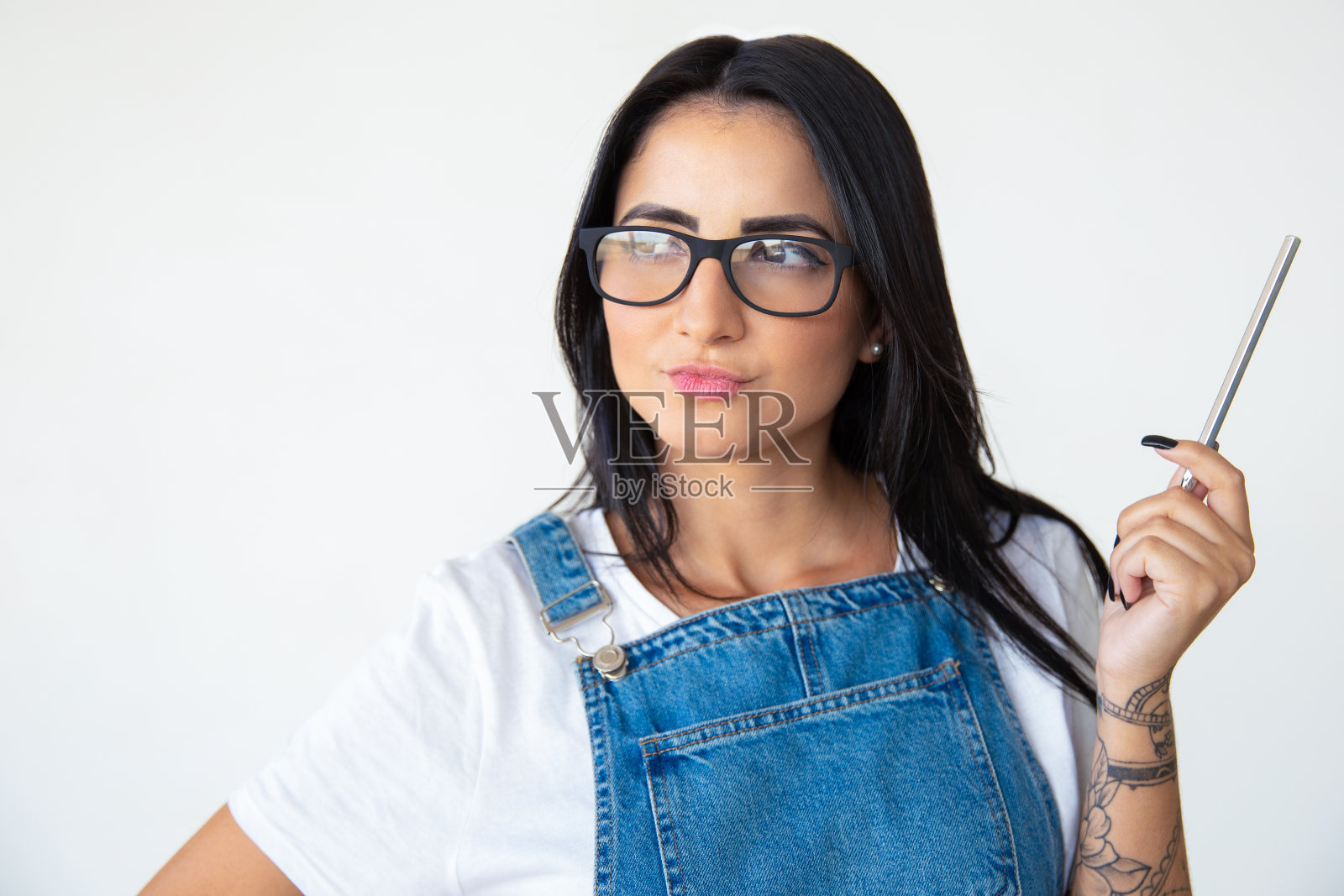 想着戴着眼镜的黑发女子，举起手拿着笔照片摄影图片