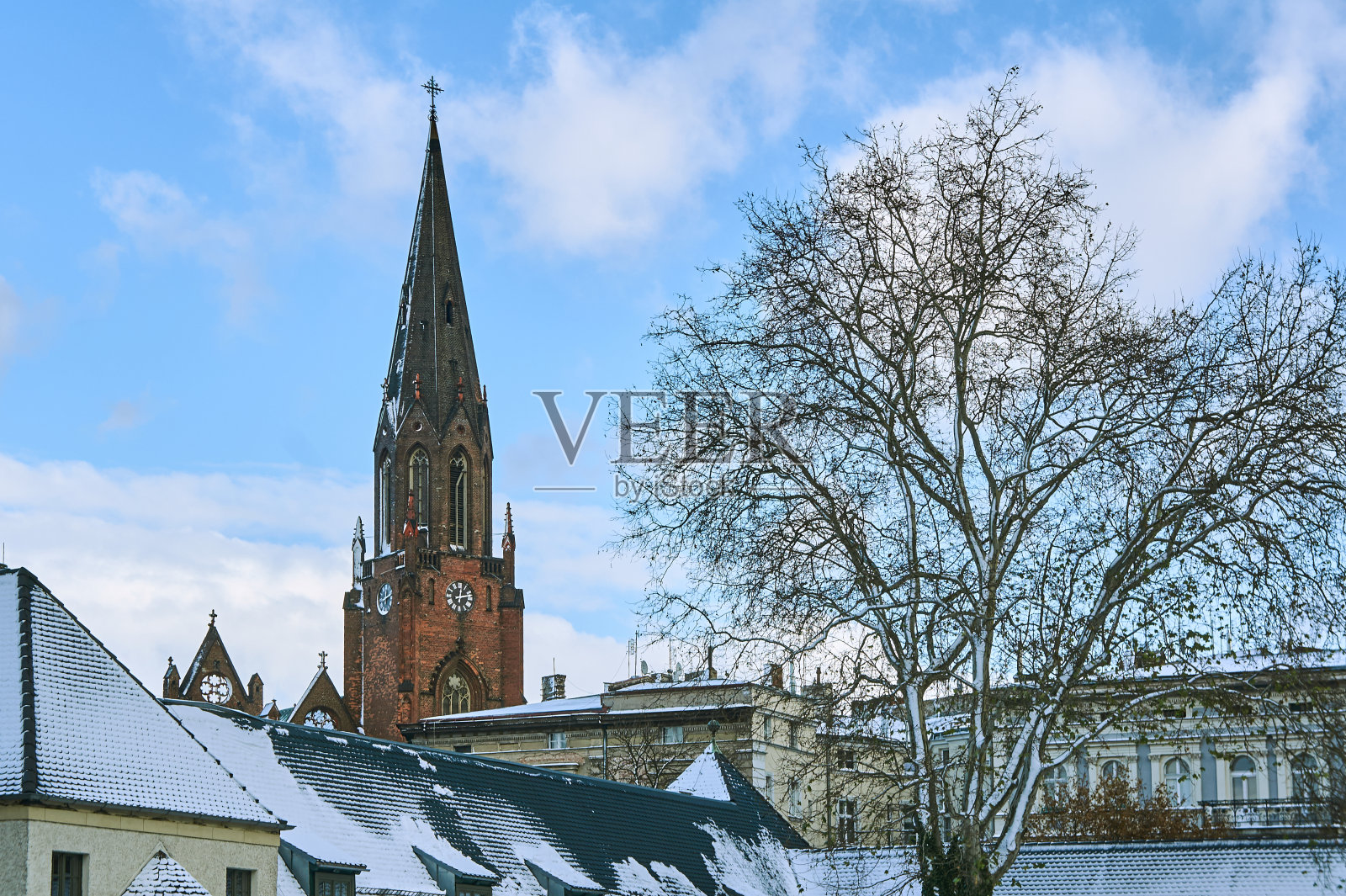 白雪覆盖的屋顶和哥特式教堂的塔照片摄影图片