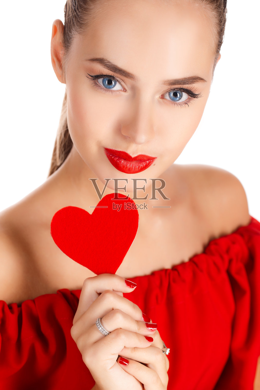 一个美丽的年轻女子的工作室肖像在一个白色的背景在工作室拿着一个红色的心在她的手中象征着爱照片摄影图片