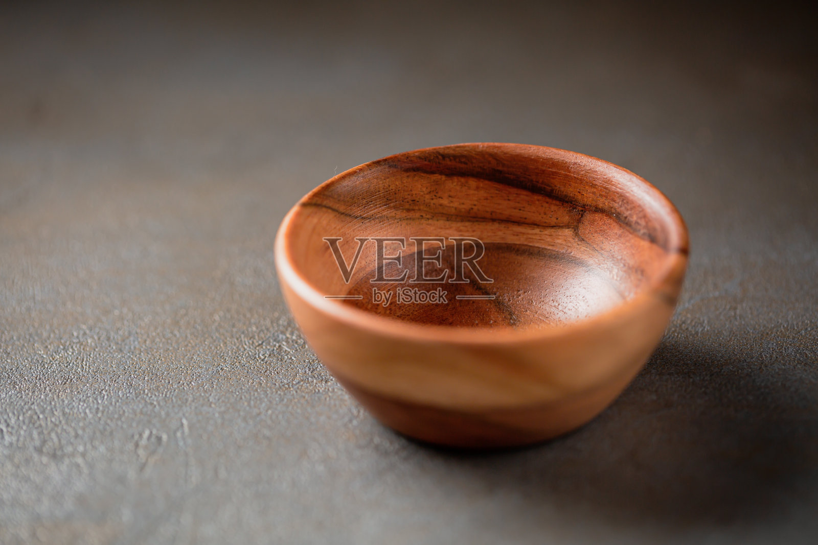 灰色的桌子上放着一只旧木碗照片摄影图片