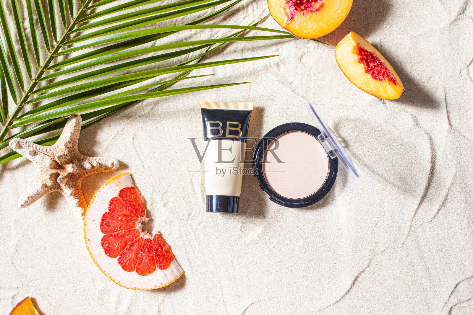 安全的太阳。皮肤护理。奶油和粉末管躺在沙滩上，周围是充满活力的水果，珊瑚和棕榈叶。照片摄影图片