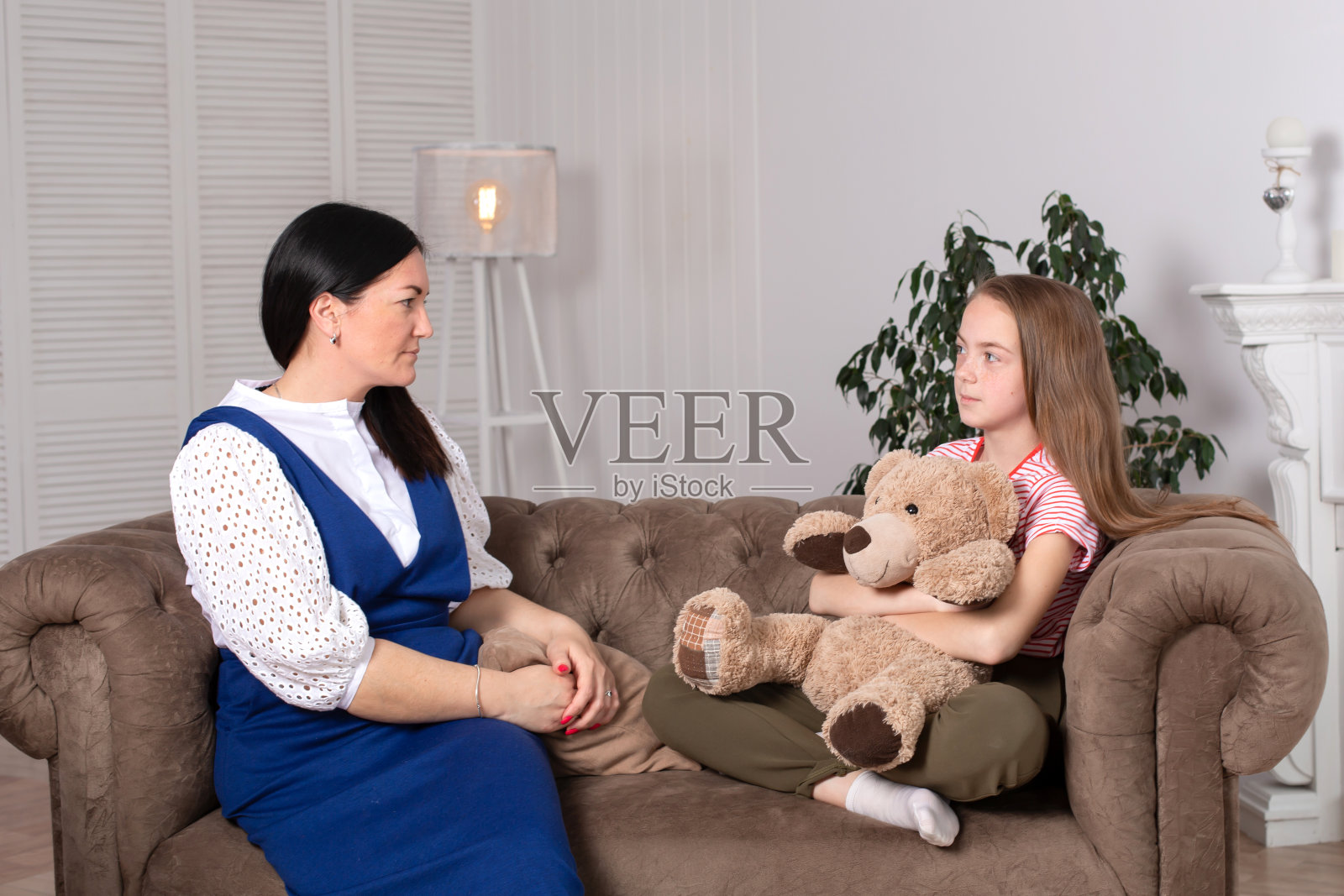 一位儿童心理学家在舒适的办公室里与一个十几岁的女孩交谈，为儿童提供心理帮助照片摄影图片