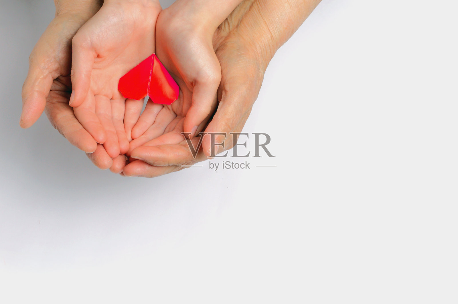 大人和小孩的手握着一颗红心照片摄影图片