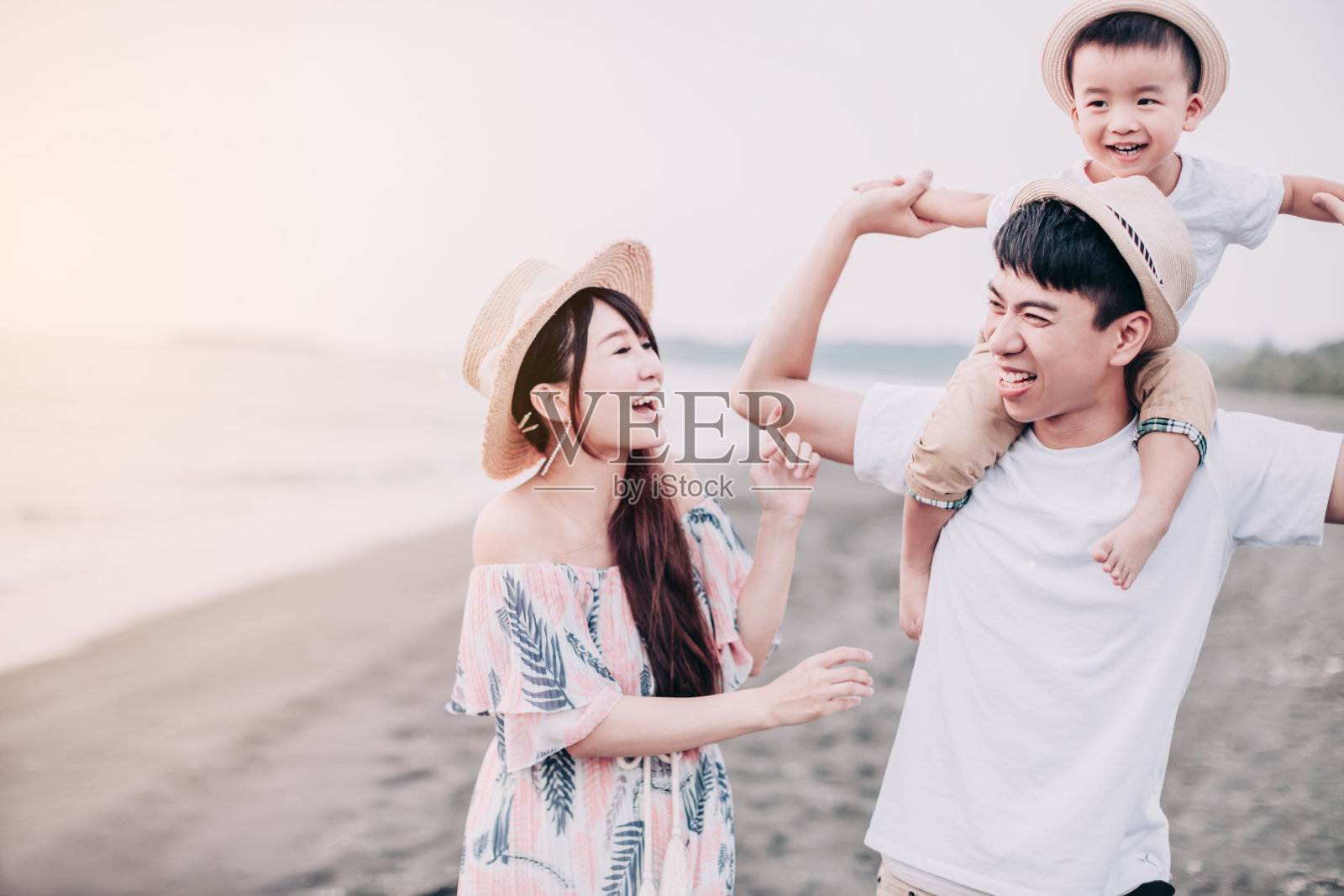 日落时分，快乐的亚洲家庭在海滩上玩耍照片摄影图片