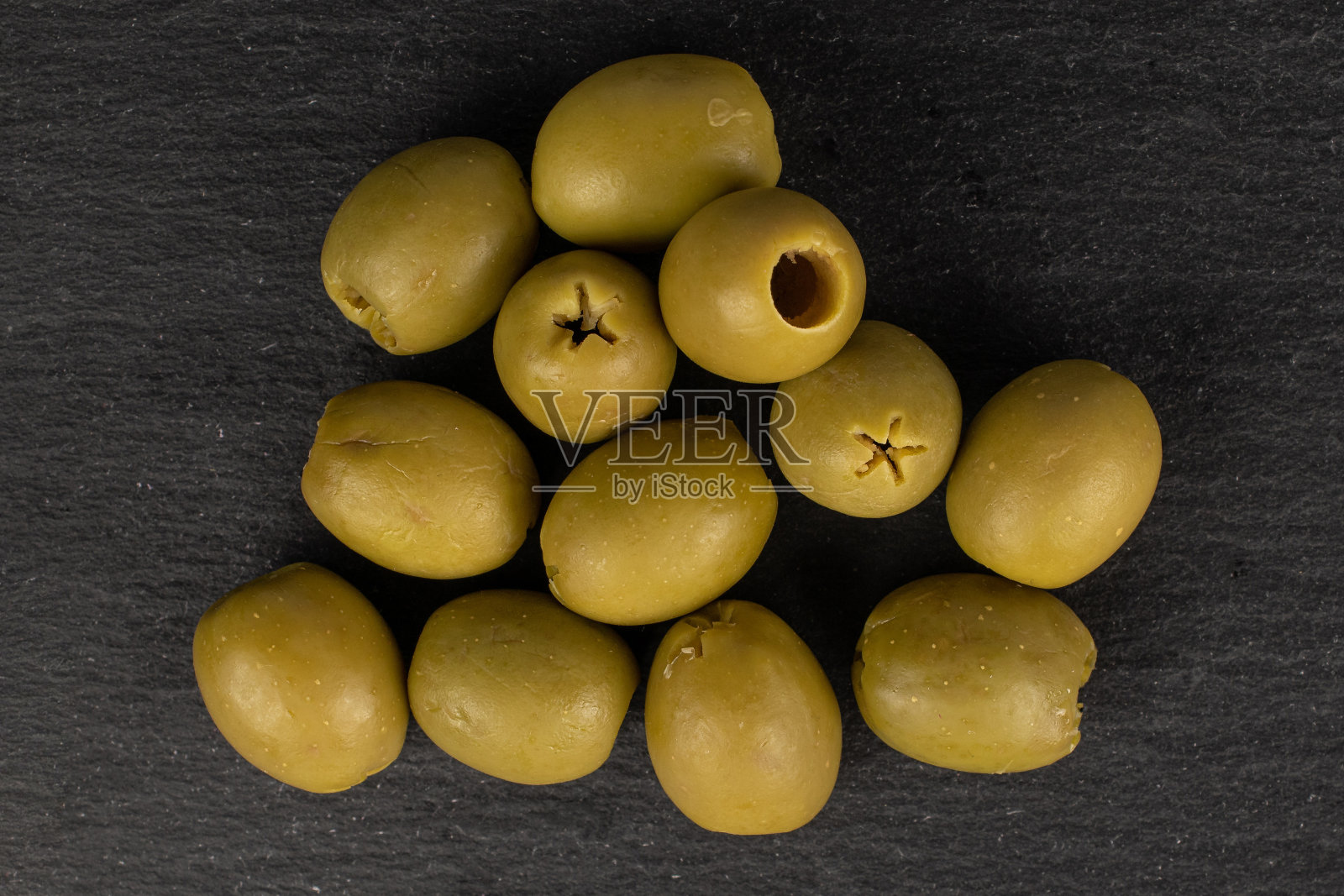 绿橄榄泡在灰色的石头上照片摄影图片