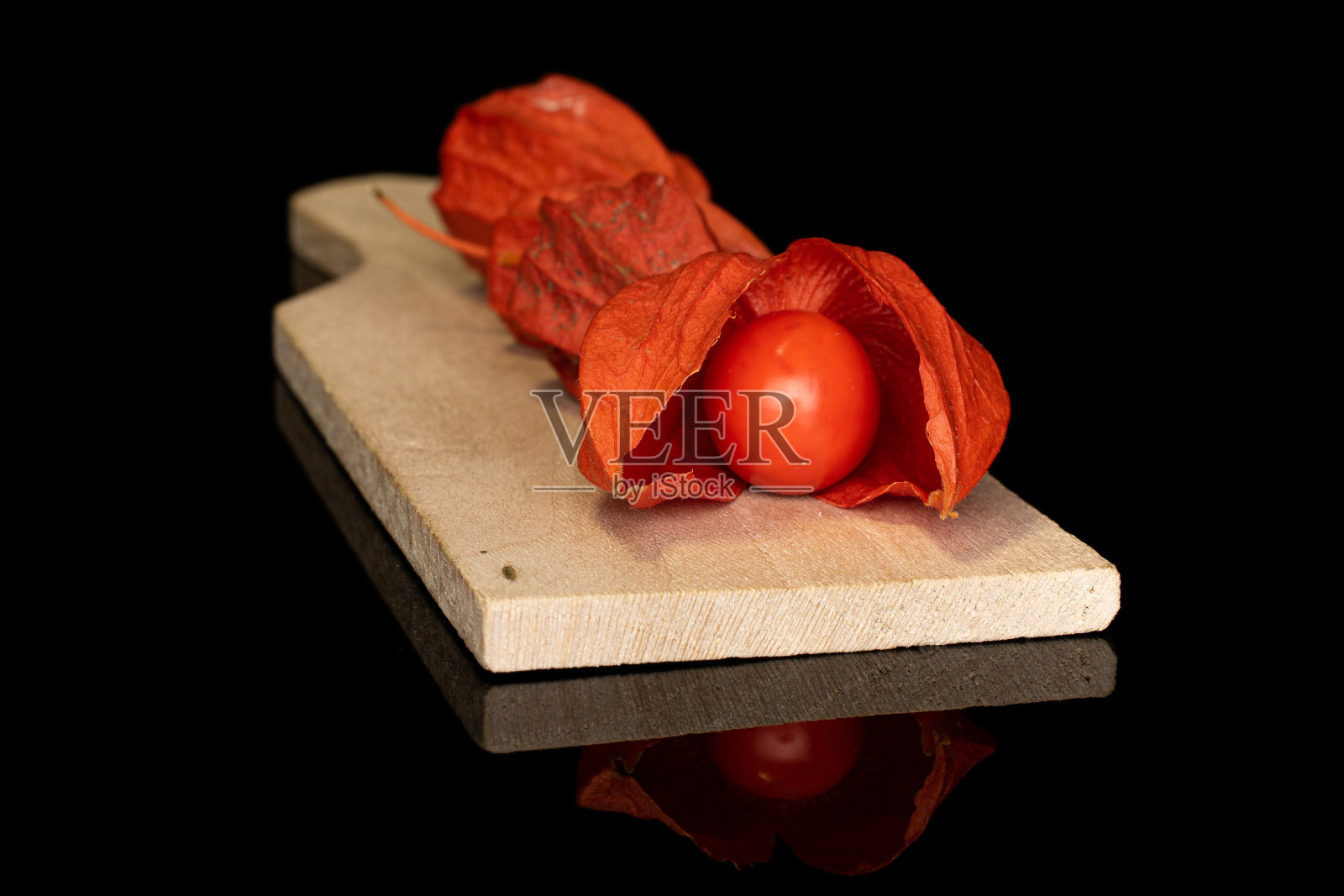 在黑色玻璃上分离出新鲜的橙色酸浆照片摄影图片